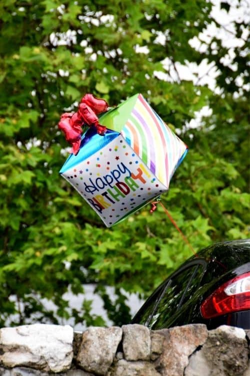 A birthday balloon hanging off of the car for a fun birthday surprise for teens.