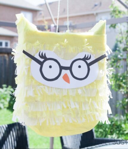 Owl pinata that is yellow and wears glasses.