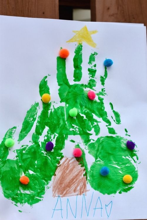 Christmas tree with fingerprints that includes three handprints and pom poms for decoration.