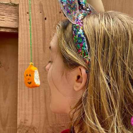 a girl getting ready to eat a pumpkin marshmallow in a fall game.