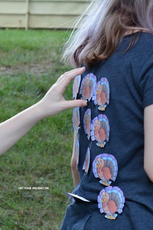 A child grabbing a turkey off of the back of the shirt while playing chase the turkey game.