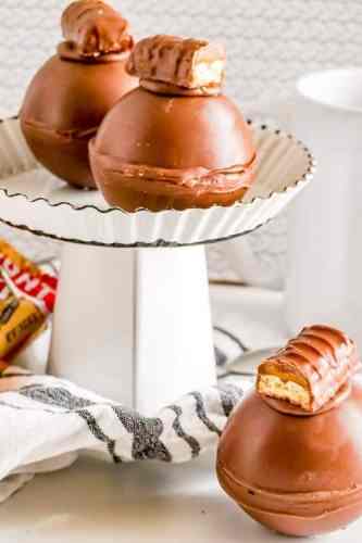 Twix hot chocolate bomb that have pieces of twix candy bar on top of them.